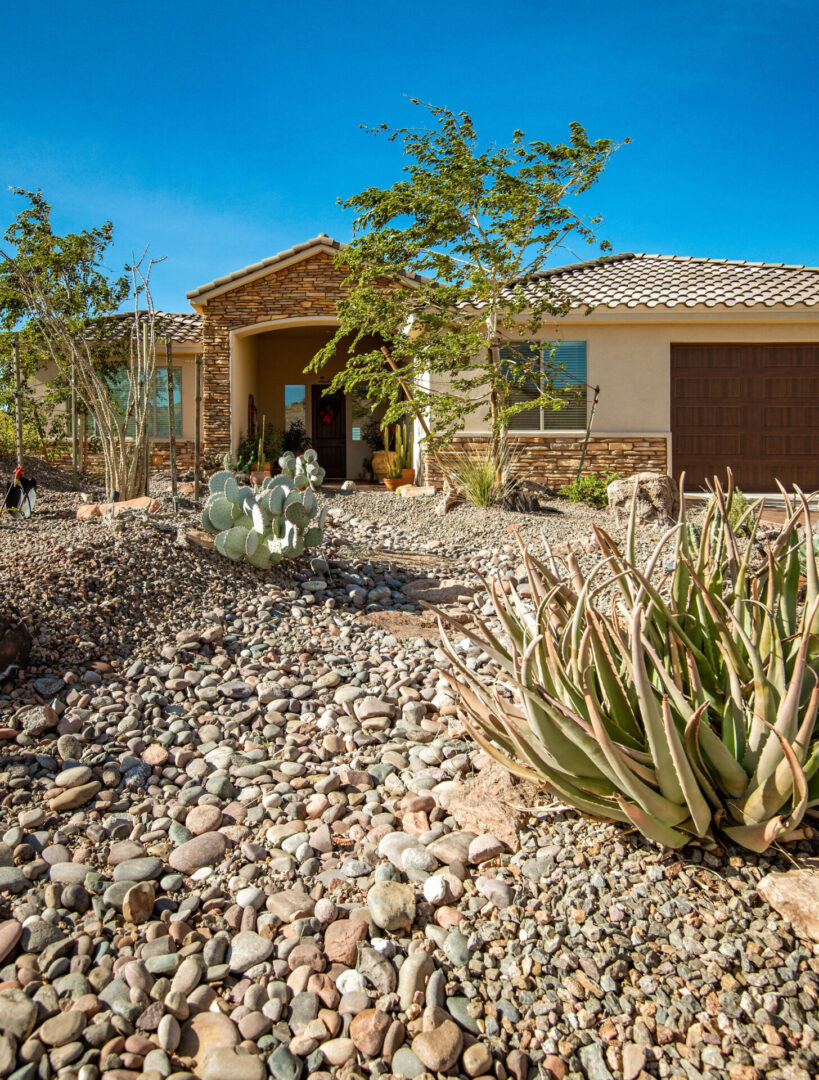 A house with many plants and rocks in front of it