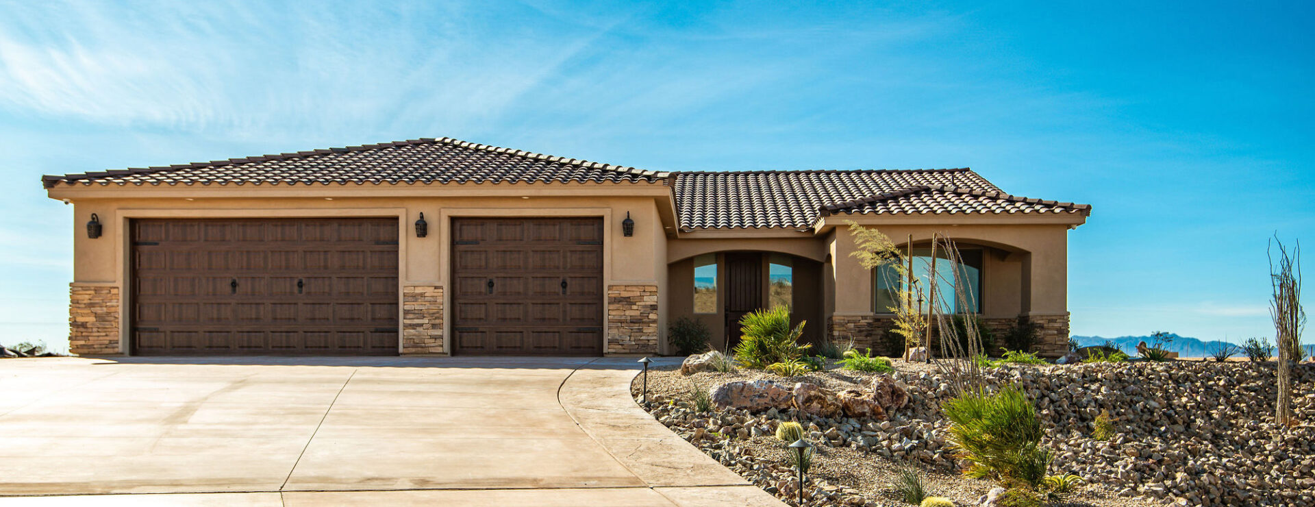 A tan house with two brown garage doors.